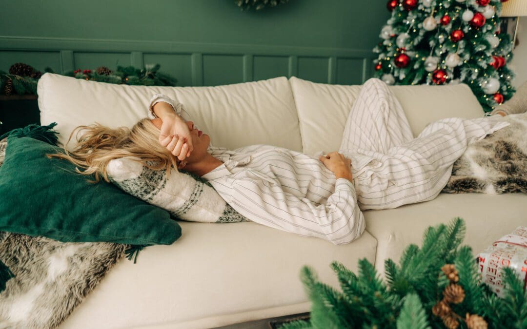 Tired grieving woman is resting lying on the sofa at Christmas